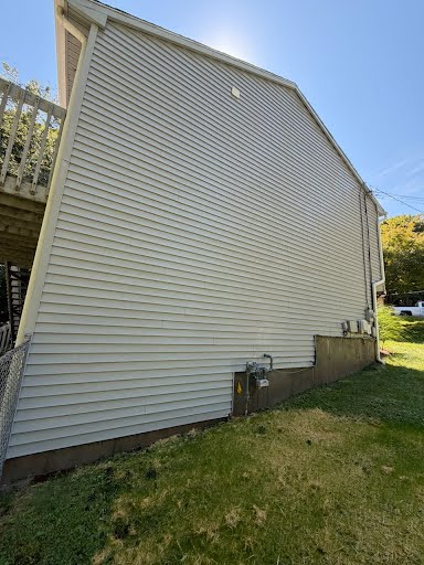 House wall before and after washing — dark growth cleaned off the siding.